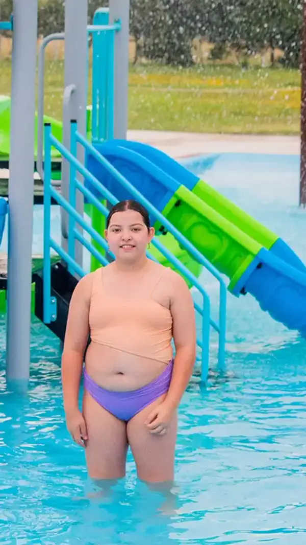 Niña en la piscina infantil junto a los juegos