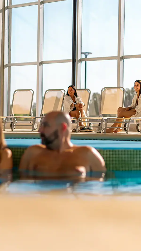 Personas en el agua termal junto a los ventanales